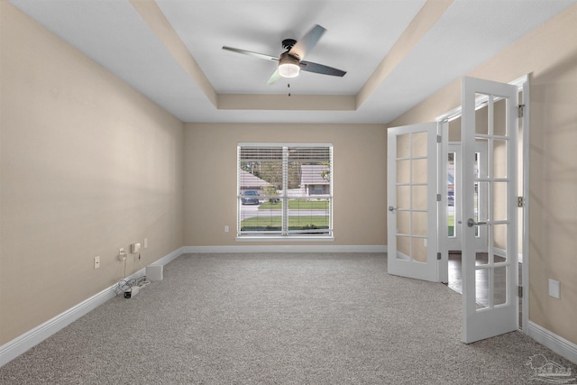 carpeted empty room featuring french doors, ceiling fan, and a raised ceiling