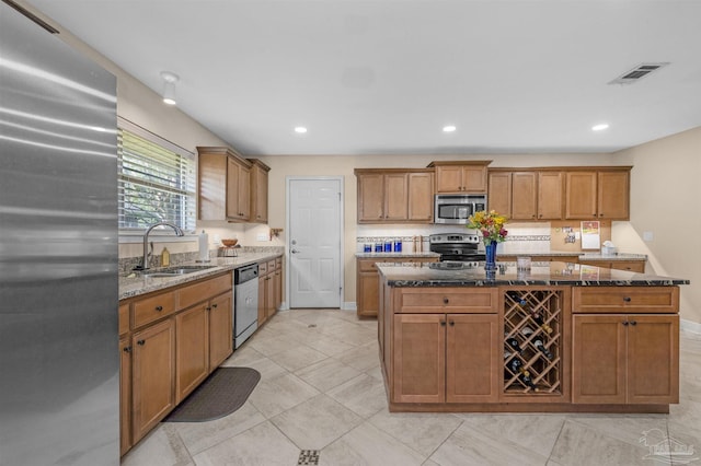 kitchen featuring sink, light tile patterned flooring, a center island, stainless steel appliances, and dark stone counters