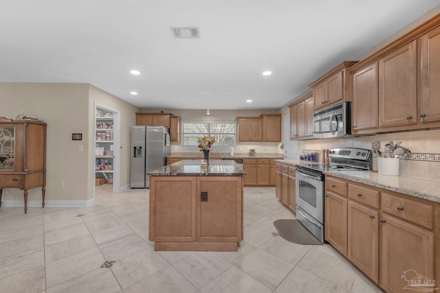 kitchen featuring a kitchen island, backsplash, light stone countertops, light tile patterned floors, and appliances with stainless steel finishes