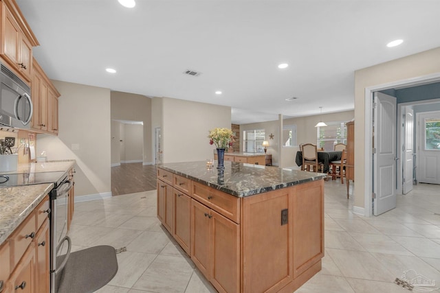 kitchen with dark stone countertops, light tile patterned flooring, appliances with stainless steel finishes, and a center island