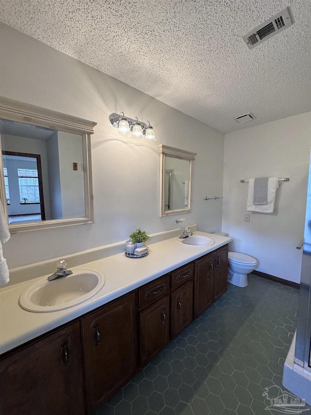 bathroom with vanity, tile patterned floors, a textured ceiling, and toilet