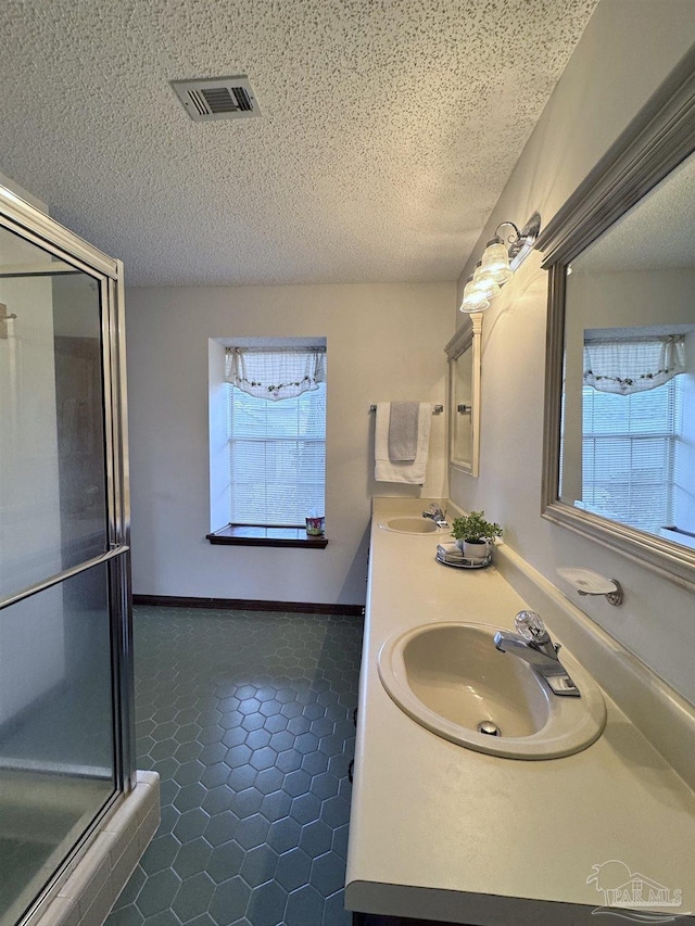 bathroom featuring vanity, a healthy amount of sunlight, an enclosed shower, and a textured ceiling