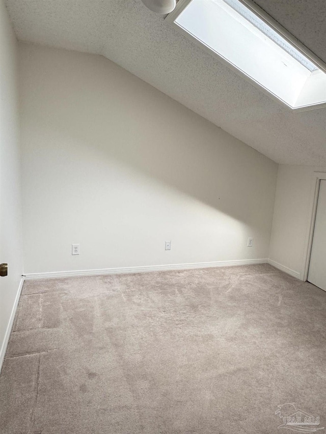 bonus room with vaulted ceiling with skylight, a textured ceiling, and carpet flooring