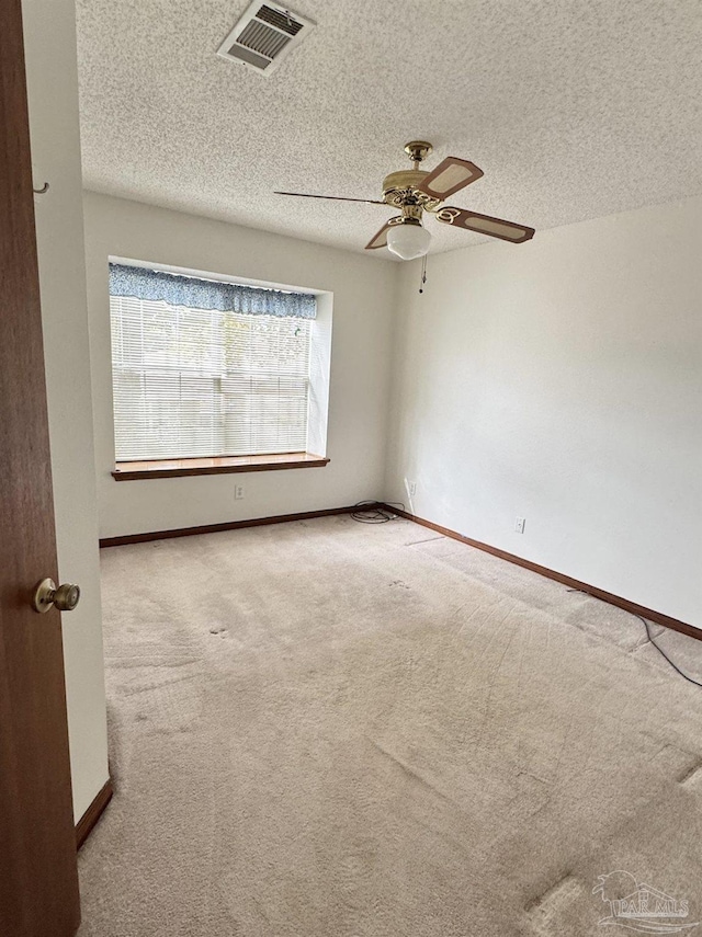 carpeted empty room with ceiling fan and a textured ceiling