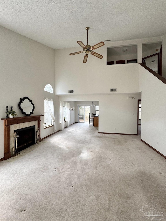 unfurnished living room featuring a textured ceiling, a high end fireplace, ceiling fan, and carpet