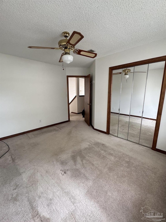 unfurnished bedroom with light colored carpet, a textured ceiling, ceiling fan, and a closet