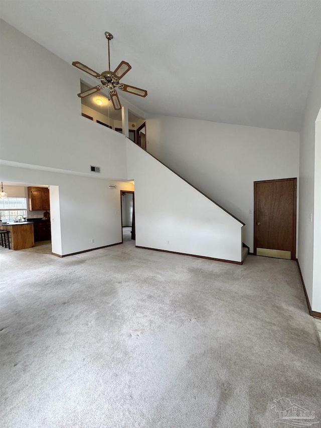 unfurnished living room featuring high vaulted ceiling, light colored carpet, and ceiling fan