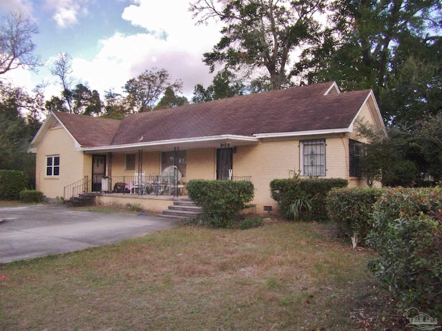 ranch-style house featuring covered porch and a front lawn