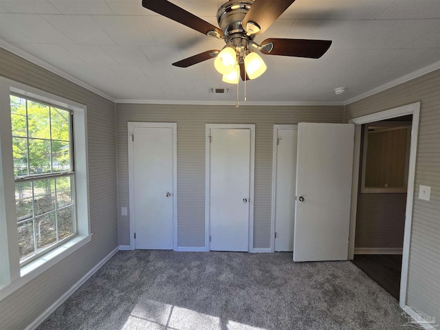unfurnished bedroom featuring carpet floors, crown molding, visible vents, baseboards, and ceiling fan