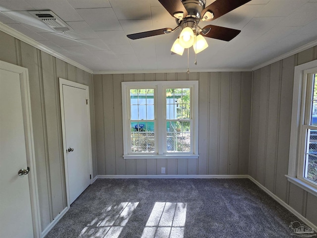 spare room featuring visible vents, crown molding, a ceiling fan, baseboards, and carpet flooring