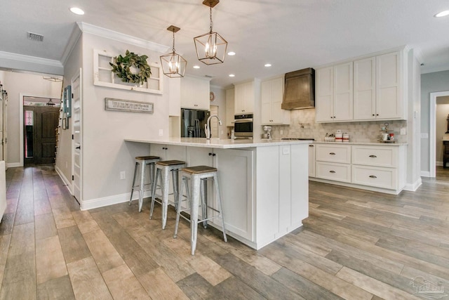 kitchen featuring pendant lighting, white cabinetry, black appliances, custom exhaust hood, and kitchen peninsula