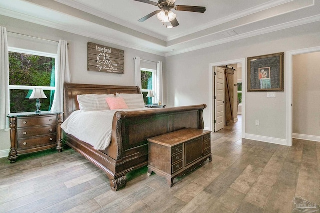 bedroom with light hardwood / wood-style flooring, ornamental molding, a raised ceiling, and ceiling fan