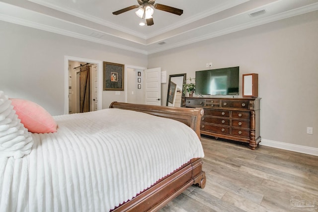 bedroom with ceiling fan, ornamental molding, a tray ceiling, and light hardwood / wood-style floors