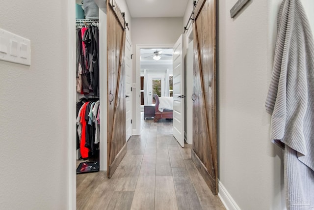 corridor with light hardwood / wood-style floors and a barn door