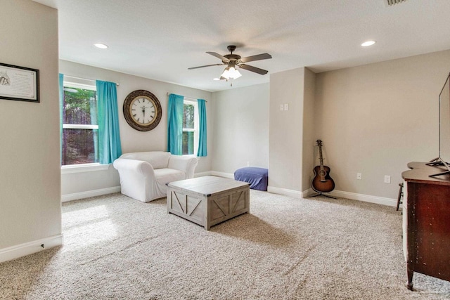 living room featuring ceiling fan, light colored carpet, and a textured ceiling