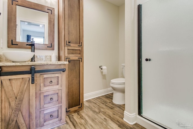 bathroom featuring walk in shower, vanity, toilet, and hardwood / wood-style floors