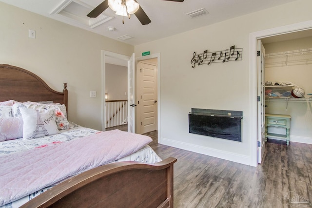 bedroom featuring a walk in closet, dark hardwood / wood-style floors, ceiling fan, and a closet