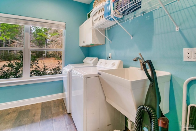 clothes washing area featuring cabinets, hardwood / wood-style floors, and washing machine and clothes dryer