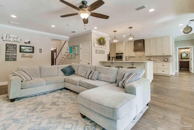 living room with crown molding, a textured ceiling, ceiling fan, and light hardwood / wood-style floors