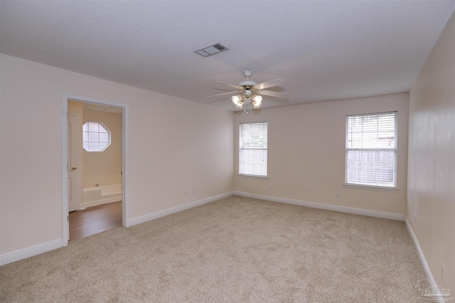 unfurnished room with light colored carpet, ceiling fan, visible vents, and a wealth of natural light