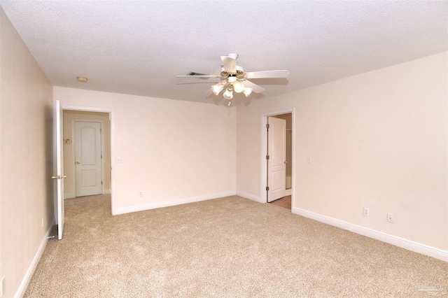 unfurnished room with a ceiling fan, baseboards, light carpet, and a textured ceiling