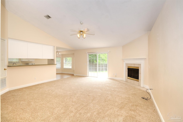 unfurnished living room with a fireplace, baseboards, ceiling fan, light colored carpet, and vaulted ceiling