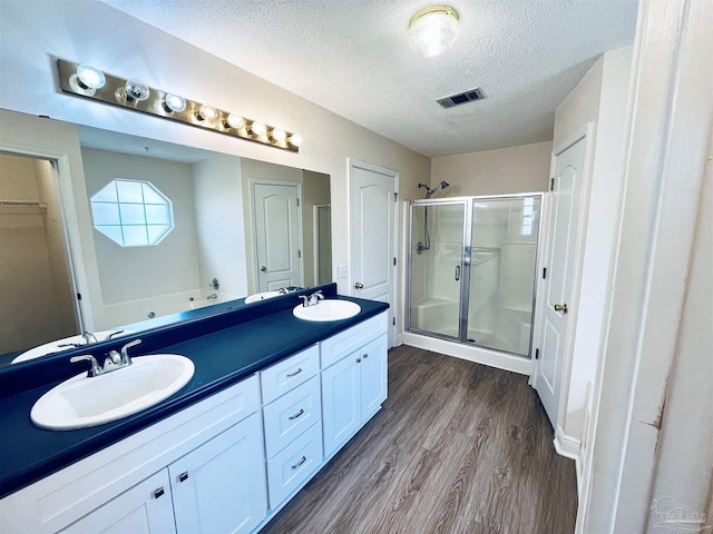 bathroom featuring visible vents, a sink, a textured ceiling, and wood finished floors