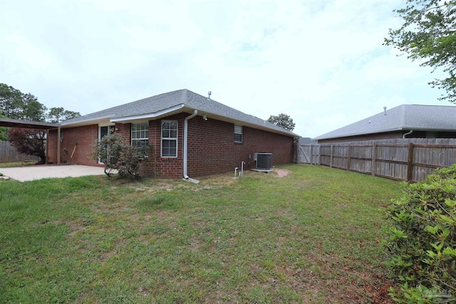view of property exterior featuring brick siding, central AC, a fenced backyard, a yard, and a patio