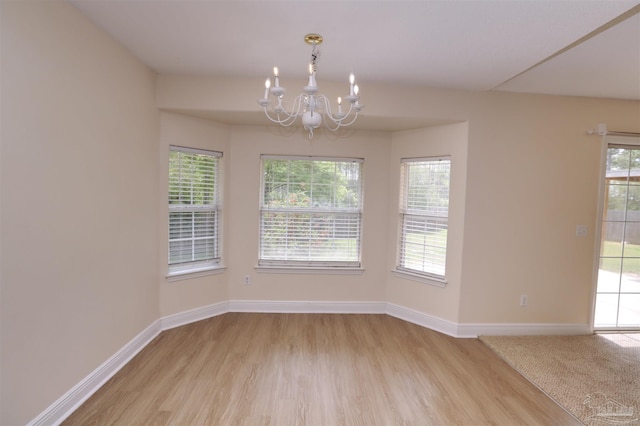unfurnished dining area featuring baseboards, a notable chandelier, and light wood-type flooring