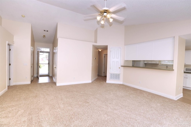 unfurnished living room with a ceiling fan, baseboards, vaulted ceiling, and light carpet
