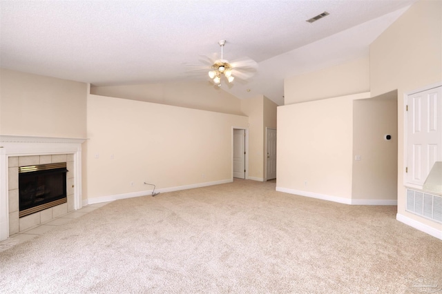 unfurnished living room with visible vents, a ceiling fan, a tile fireplace, and light colored carpet