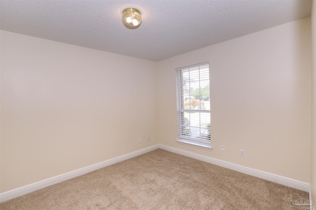 unfurnished room featuring a textured ceiling, baseboards, and light carpet