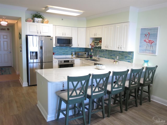 kitchen with a peninsula, light stone counters, stainless steel appliances, and a sink