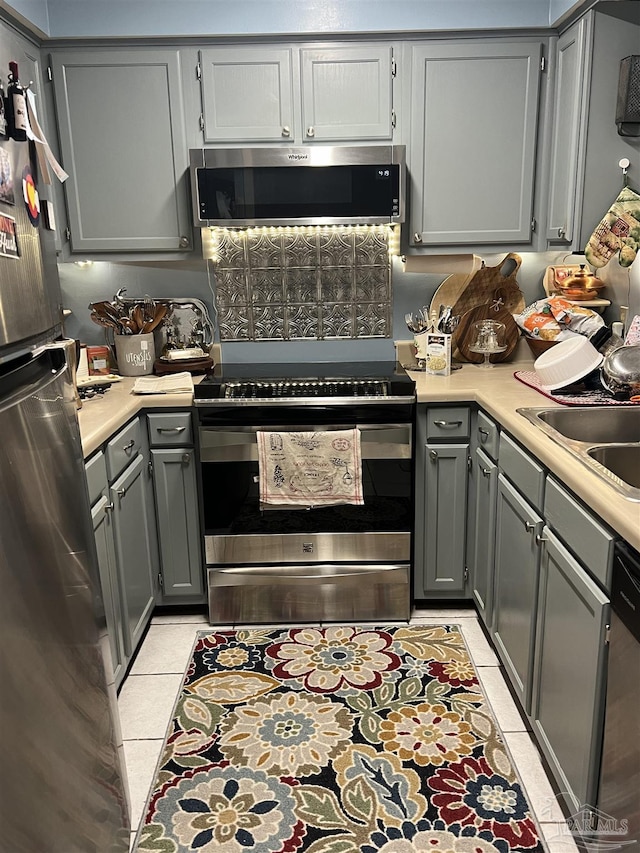 kitchen featuring stainless steel appliances, gray cabinets, light countertops, and light tile patterned floors