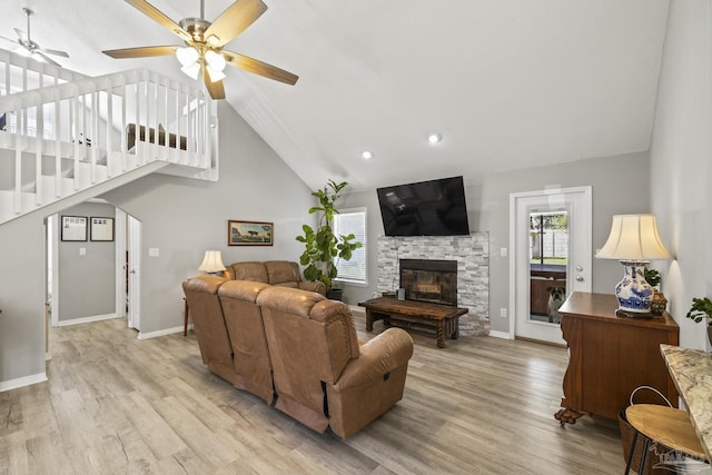 living room featuring a fireplace, light wood-style flooring, a ceiling fan, and baseboards