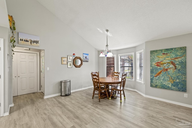 dining area with light wood-style flooring, a textured ceiling, and baseboards