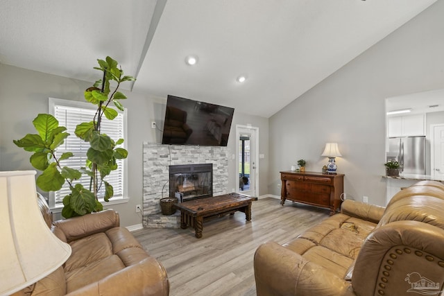 living room featuring light wood finished floors, baseboards, lofted ceiling, a stone fireplace, and recessed lighting