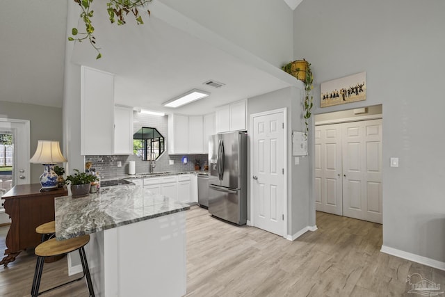 kitchen with visible vents, light stone counters, plenty of natural light, stainless steel appliances, and a peninsula