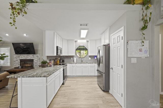 kitchen featuring visible vents, light stone counters, open floor plan, stainless steel appliances, and decorative backsplash