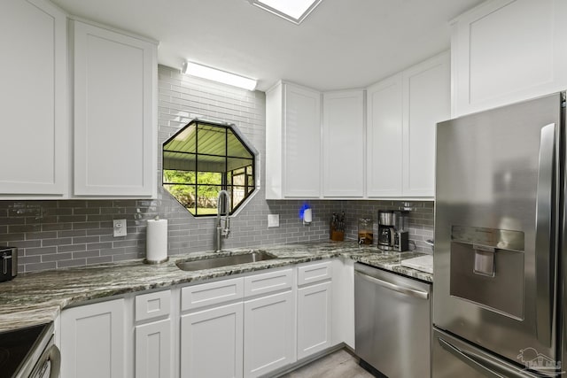 kitchen featuring decorative backsplash, white cabinets, appliances with stainless steel finishes, and a sink