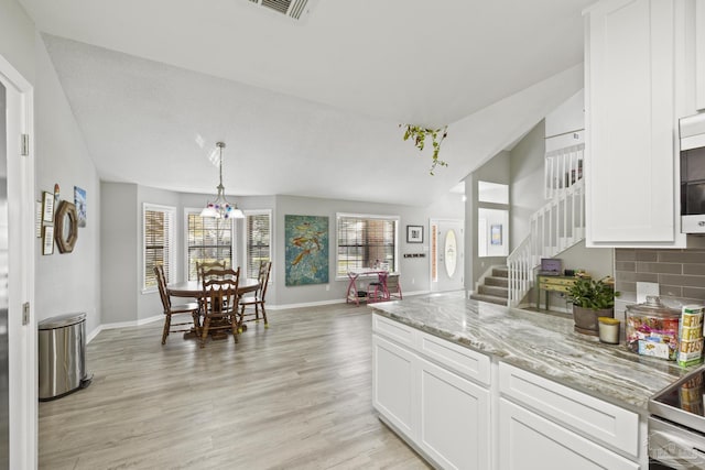 kitchen with lofted ceiling, light wood-style flooring, tasteful backsplash, and white cabinets