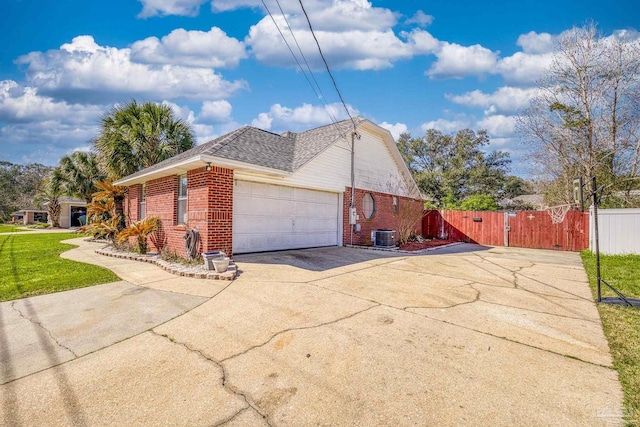 view of home's exterior featuring brick siding, an attached garage, driveway, and a gate