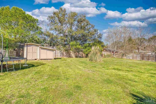 view of yard featuring an outdoor structure, a trampoline, a fenced backyard, and a shed