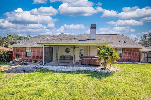 back of property featuring fence, a yard, a chimney, a hot tub, and a patio area