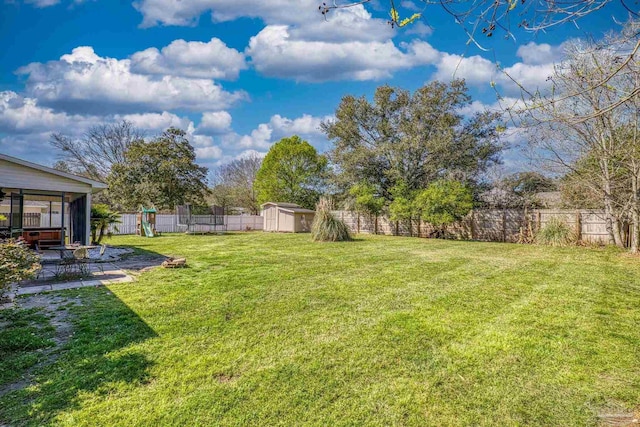 view of yard featuring an outbuilding, a fenced backyard, a shed, and a patio area