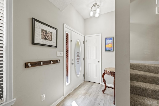 entrance foyer with light wood-style flooring, stairs, and baseboards