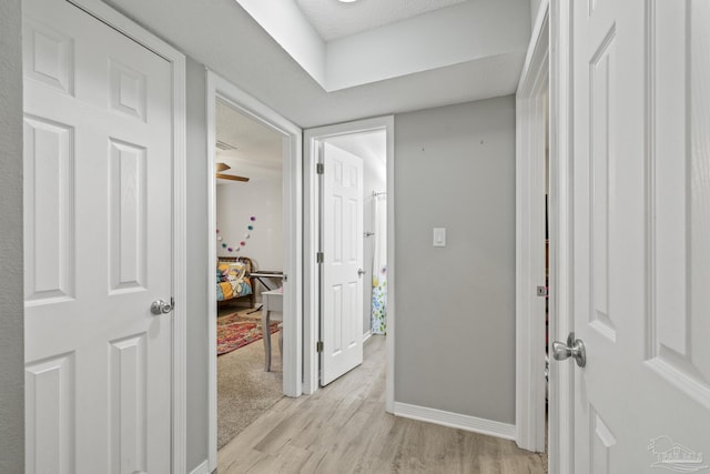 corridor featuring light wood-type flooring and baseboards