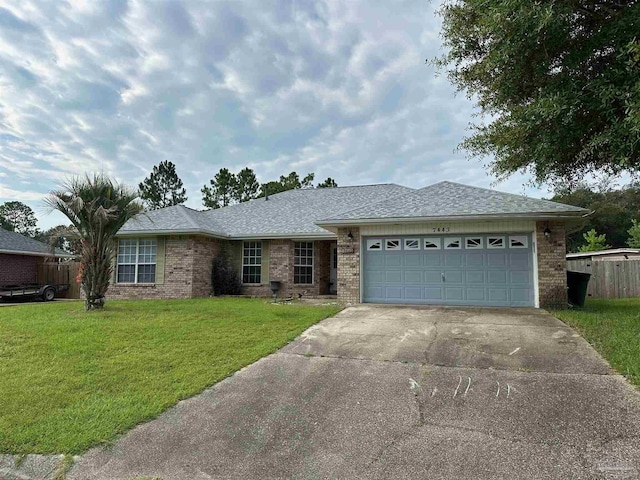 ranch-style home with brick siding, a shingled roof, concrete driveway, an attached garage, and a front yard