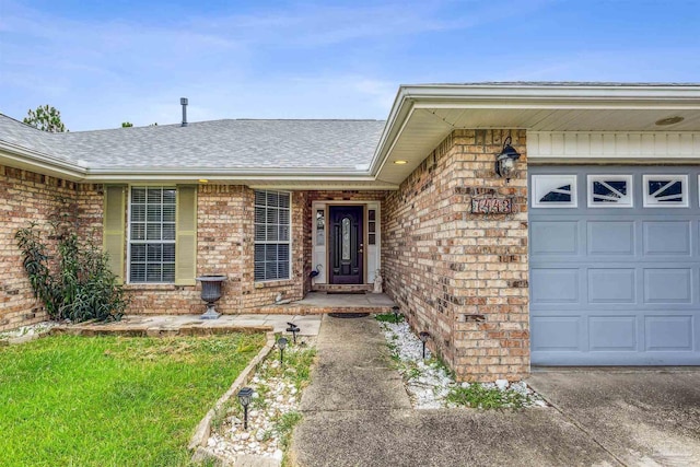 entrance to property with a garage, brick siding, and roof with shingles