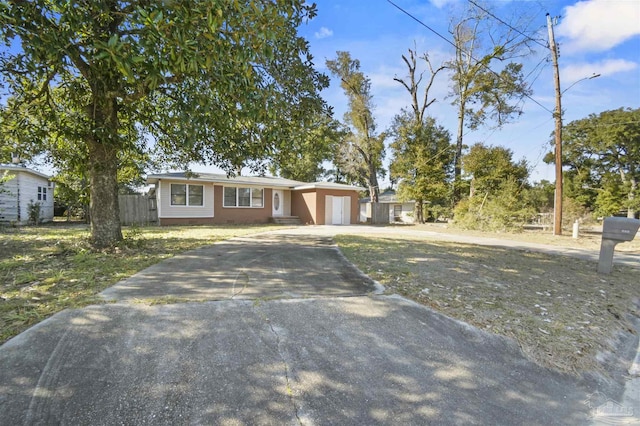 ranch-style home featuring driveway, a garage, crawl space, fence, and a front lawn